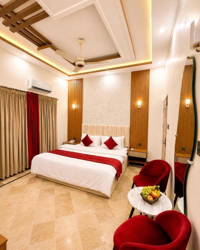 a hotel room with a bed and red chairs at Holiday One Hotel & Suites - Gulshan-3 in Karachi