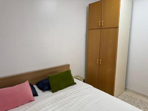 a bedroom with a white bed with a green pillow and a cabinet at 8minit walk to jongke in Malacca