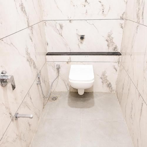 a white bathroom with a toilet and a shower at Hotel Mangla Inn - Dwarka in Dwarka