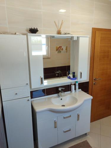 a white bathroom with a sink and a mirror at Pansion Ajlin in Blagaj