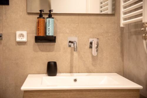 a bathroom with a white sink and a bottle on the wall at Aellia Bay Residences in Alinda