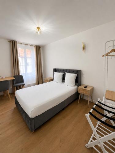a bedroom with a bed and a desk and a chair at Hôtel JurJura in Dole