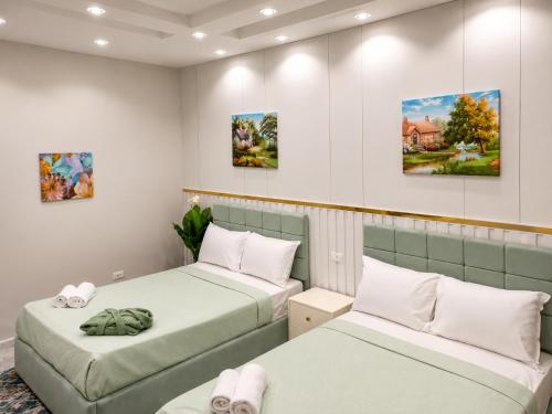 two beds in a room with paintings on the wall at Tahrir Residence -"Marriage Certificate Required for Couples" in Cairo