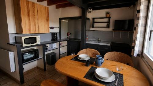 a small kitchen with a wooden table and chairs at Duplex le Randonneur - Les Apparts du Sancy in Chastreix