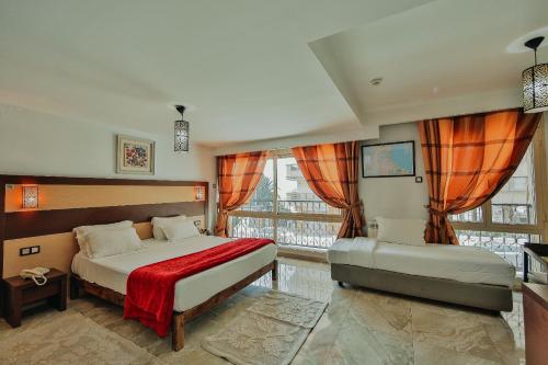 a bedroom with two beds and a large window at Hôtel Telemly - Chaine El Djazair in Alger