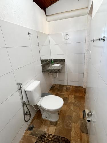 a white bathroom with a toilet and a sink at Chalés Terra Santa Capitólio in Capitólio