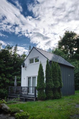 a white house with a fence and some trees at Natura Taszów in Lewin Kłodzki