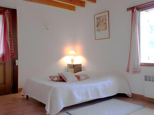 a white bedroom with a bed with two pillows at Les 3 Vignobles in Pardaillan