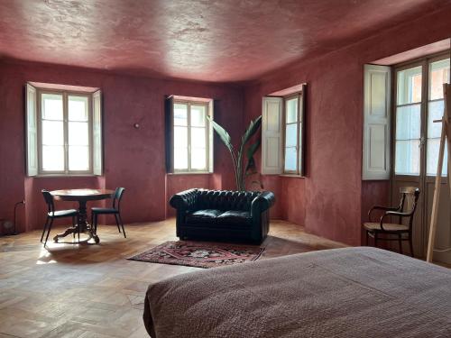 a bedroom with a couch and a table and windows at Casa Piumogna in Faido