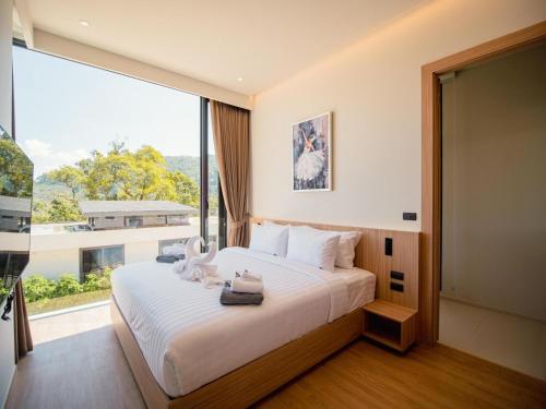 a bedroom with a large bed with a large window at Villa Kauri 3BR Pool Villa at Aileen Naithon in Ban Sakhu