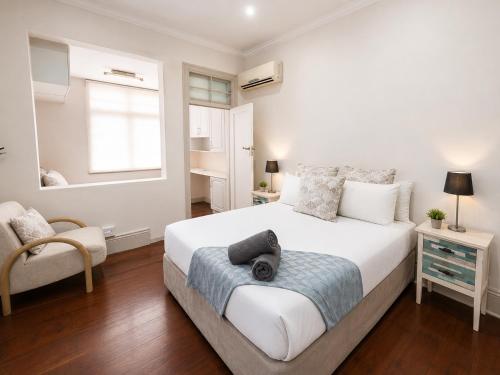a bedroom with a large white bed and a chair at Musgrave Escape - 3 bedroom home with tennis court in Durban