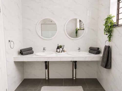 a bathroom with two sinks and two mirrors at Musgrave Escape - 3 bedroom home with tennis court in Durban