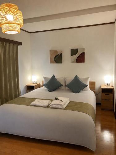 a bedroom with a large white bed with two lamps at HOUSE26 Private Villa near Green Expo Yokohama in Machida