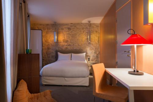 a bedroom with a bed and a desk with a lamp at Hotel Danemark in Paris