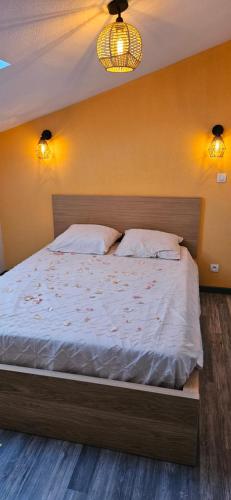 a bedroom with a bed with white sheets and two pillows at Appartement près des Grands Buffets climatisé in Narbonne