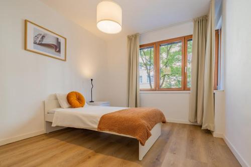 a white bedroom with a bed and a window at Pure living Apartment in Zürich Oerlikon in Zurich