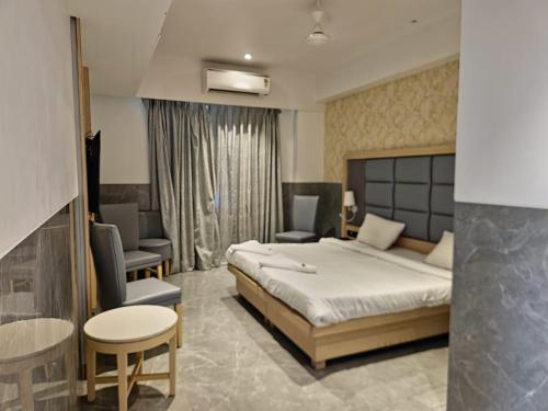 a bedroom with a bed and chairs and a table at Hotel Suncity Residency in Kālundri