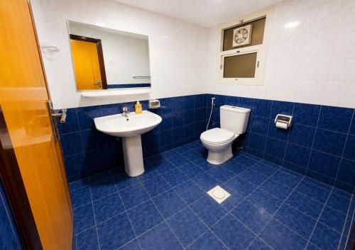 a blue tiled bathroom with a toilet and a sink at TIDY Premium Hostel, Sharjah in Sharjah