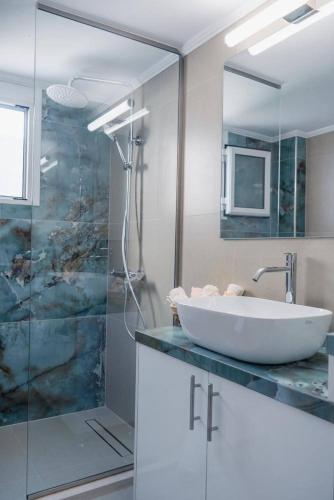 a bathroom with a sink and a glass shower at Vickys Apartment Diakopto in Diakopto