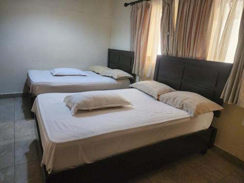 three twin beds in a room with windows at Hidden Gem With Accomodation, Restaurant, Bar & Spa in Nairobi