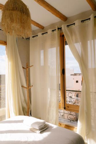 a bedroom with a bed and a large window at The Lodge - Boutique Hotel and Creative Residency in Tamraght Ouzdar