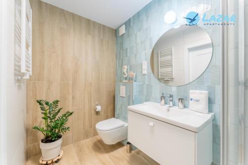 a bathroom with a toilet and a sink and a mirror at Lazar Apartamenty Polanki Aqua in Kołobrzeg
