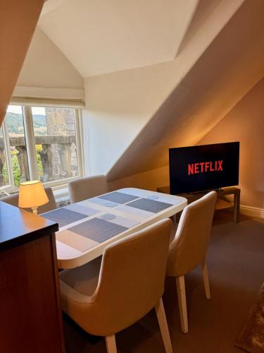 a dining room with a table and chairs and a netflix sign at Bagshaw Hall in Bakewell