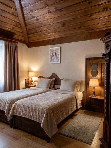 a bedroom with a large bed with a wooden ceiling at Костовският хан in Chepelare