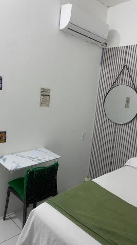 a room with two beds and a table and a mirror at Suíte Standard Privado in Vitória