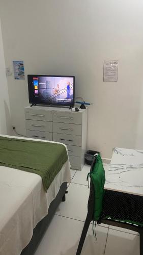 a living room with a television and a bed and a bedskirts at Suíte Standard Privado in Vitória