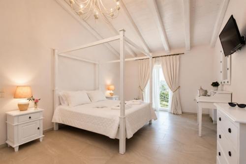 a white bedroom with a white canopy bed and a sink at Villa Frosso in Kalami