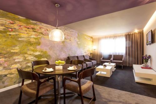 a living room with a table and chairs and a painting at Grand Hotel Plovdiv in Plovdiv