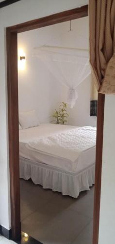 a bedroom with a white bed with a wooden frame at 53 Villa in Habaraduwa Central