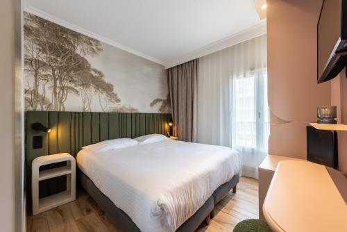 a hotel room with a bed and a painting on the wall at Le Petit Prince in Sainte-Maxime