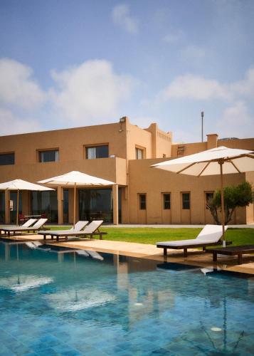 a resort with a swimming pool with umbrellas and chairs at The Riad by Blue Waves in Agadir
