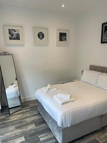 a white bedroom with a bed and a mirror at Elder Park Apartments in Glasgow