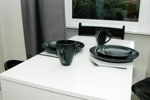 a white table with black plates and utensils on it at Elder Park Apartments in Glasgow