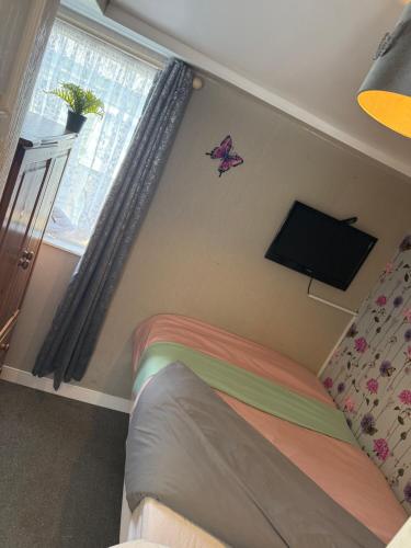 a bedroom with a bed and a tv on the wall at The Butterfly in Leysdown-on-Sea