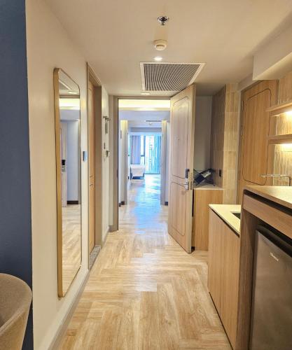 a kitchen with wooden floors and a hallway with a mirror at The Quarter Ladprao by UHG in Bangkok