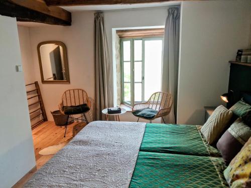 a bedroom with a bed and chairs and a window at Chateau d'Impasse in Laferté-sur-Amance