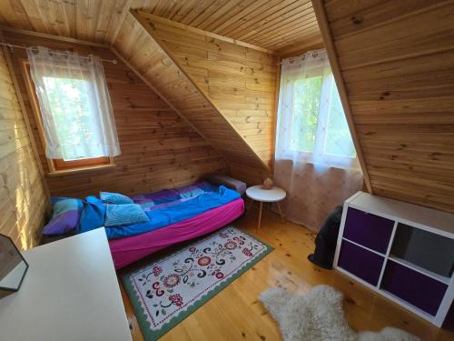 an attic room with a bed in a wooden house at Urokliwy domek Młynarze in Młynarze