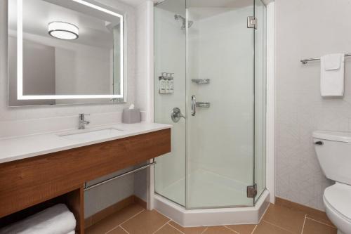 Holiday Inn Express Olean, NY في أوليان: حمام مزود بمغسلة ودش