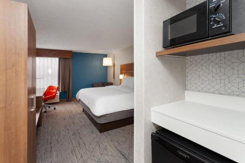 Holiday Inn Express Olean, NY في أوليان: غرفة فندق بها سرير وجهاز تلفزيون