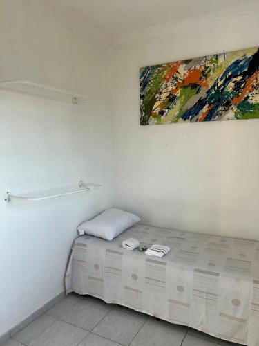 a room with a bed with a painting on the wall at Quarto econômico e confortável in Hortolândia