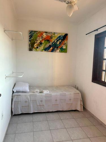 a bed in a room with a painting on the wall at Quarto econômico e confortável in Hortolândia