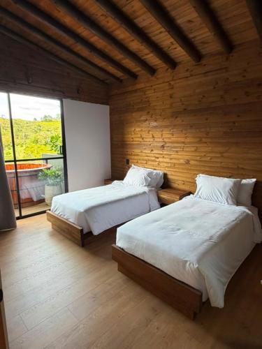 two beds in a bedroom with a wooden wall at Lagoa by Loop in Horizonte