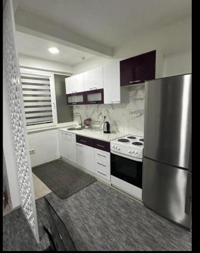 a kitchen with white cabinets and a stainless steel refrigerator at Apartment Eneya in Pazarić