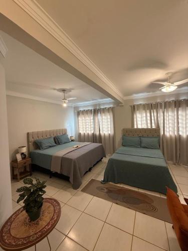 a bedroom with two beds and a table in it at Villa das Calliandras in Chapada dos Guimarães