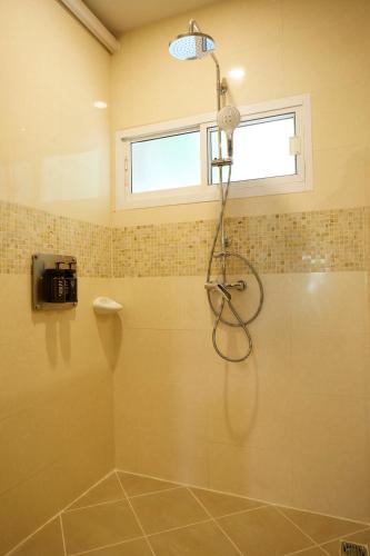 a shower stall in a bathroom with a window at Rocco Hotel Bangsaen in Ban Laem Thaen