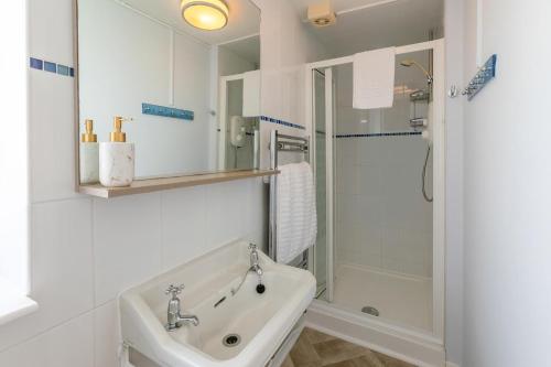 a white bathroom with a sink and a shower at 4 Bed in Looe oc-l30051 in Looe